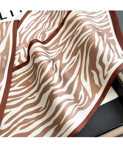 Detalle de bufanda de seda con estampado de cebra, letras SOTIME y ribete marrón oscuro