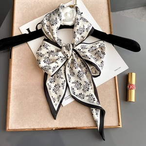 Detail of silk skinny scarf with paisley pattern tied in a bow on a black hanger