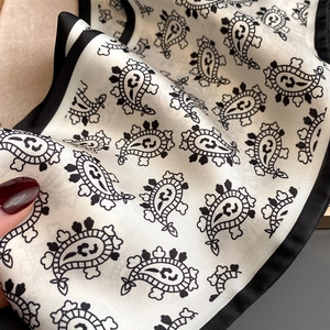 Detail of silk satin scarf with black paisley print and elegant border finish