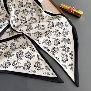 Close-up of ivory silk scarf with black paisley pattern and wide black satin border