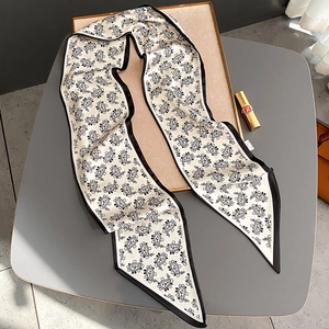 Detailed view of paisley print silk neck scarf with contrast black border edges