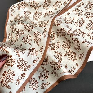 Macro detail of silk scarf showing bohemian paisley print and smooth satin texture