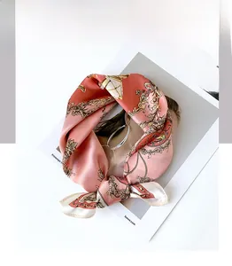 Detail of coral silk scarf with golden carriage patterns on a fashion magazine