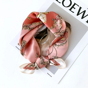 Silk scarf with coral pink baroque carriage patterns displayed on a fashion magazine