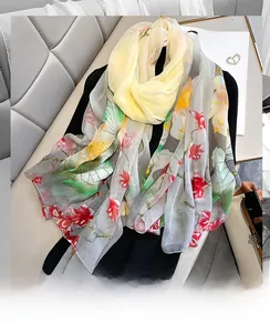 Detailed view of lightweight lotus print silk scarf with floral patterns on gray fabric