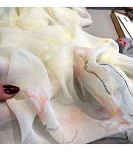 Detailed view of semi-transparent floral silk scarf with elegant orange lotus pattern