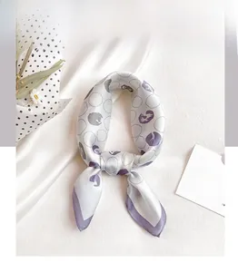 Detailed view of lilac and ivory silk scarf with abstract polka dots tied in a bow