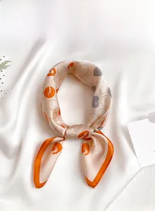 Detailed view of champagne silk square scarf with orange and grey abstract polka dot pattern