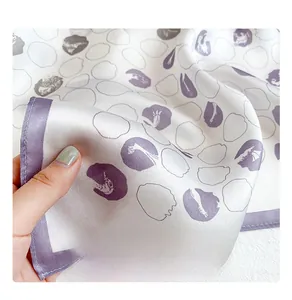 Close-up of white silk scarf with purple abstract pattern and fine machine-hemmed edges