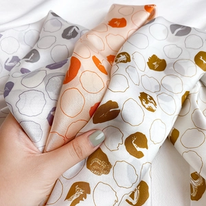 Detail of four silk scarves featuring abstract dot patterns and a smooth satin texture