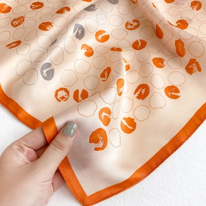 Detail of silk scarf showing orange polka dot patterns and soft texture with elegant drape