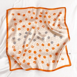Close-up of ivory and orange silk scarf featuring modern polka dot patterns and rolled edges