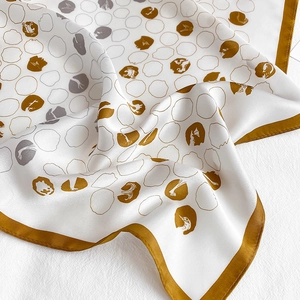 Detail of silk scarf with gold edge, white silk texture, and abstract gold circles