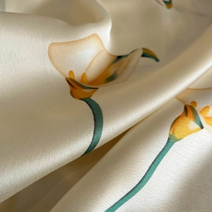 Macro detail of yellow calla lily print on soft pearl white faux silk fabric