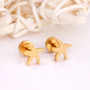 Macro view of gold starfish earrings with a matte sandblasted finish on a white surface