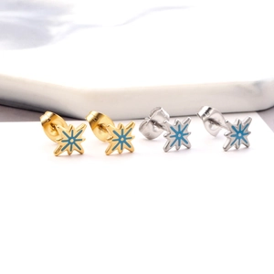 Macro shot of stainless steel star stud earrings with blue enamel detailing in gold and silver