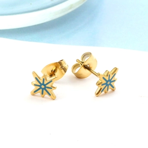 Macro shot of gold sunburst star stud earrings with blue enamel detailing and butterfly backs