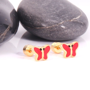 Detailed macro shot of sweet golden butterfly stud earrings with red enamel and black dots
