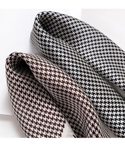 Detailed close-up of premium houndstooth silk scarves with smooth texture and glossy finish
