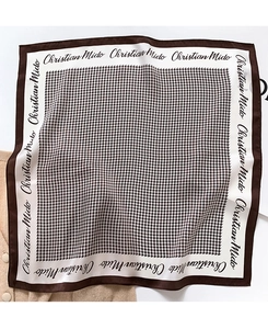Detailed close-up of houndstooth silk scarf on beige knit background with brown borders