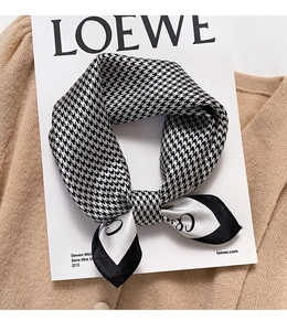 Detail of houndstooth silk scarf with letter C print on elegant beige knit background
