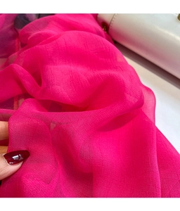 Close-up of hot pink floral silk scarf featuring elegant crinkle texture and sheer fabric