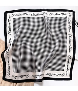 Detailed view of square silk scarf with classic black and white houndstooth pattern