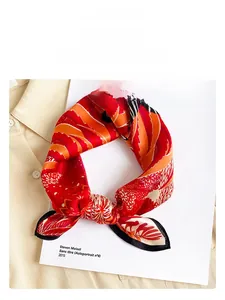 Detailed close-up of a printed silk scarf with tropical leaf patterns on a white book