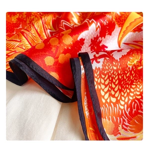 Detailed close-up of premium silk scarf featuring abstract floral prints and black rolled hem