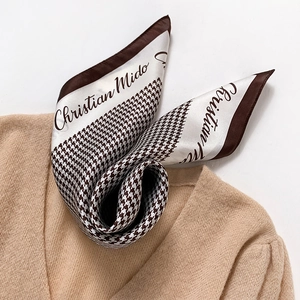 Houndstooth silk scarf with brown border styled on a beige knitted sweater neck
