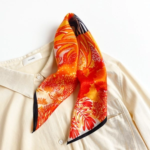 Elegant silk scarf with bright floral patterns tied on a beige shirt collar