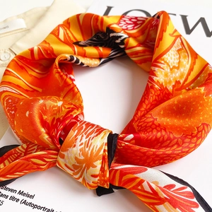 Detailed view of silk scarf with orange zebra and floral prints on fashion magazine