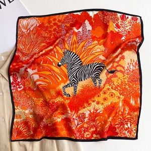 Detailed close-up of a square silk scarf featuring a zebra and tropical jungle floral print