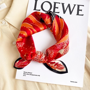 Elegant silk square scarf with red floral patterns knotted on a yellow shirt