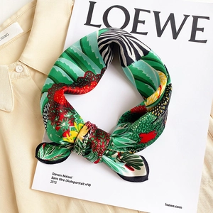 Close-up of silk scarf with green jungle print and zebra pattern on a soft beige shirt