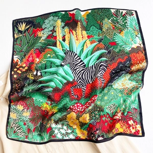 Close-up of artistic silk scarf featuring tropical floral patterns and zebra illustration