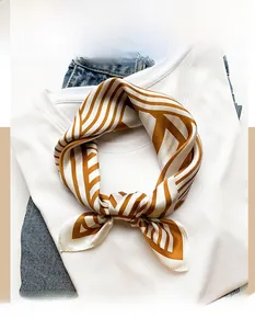Close-up of brown and white striped silk scarf knotted on a white T-shirt and denim