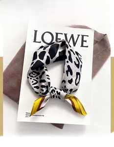 Detail of leopard print silk scarf flat lay on a magazine and knit sweater