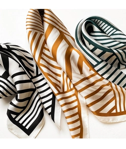 Close-up of geometric striped silk scarves in black, yellow, and green colors