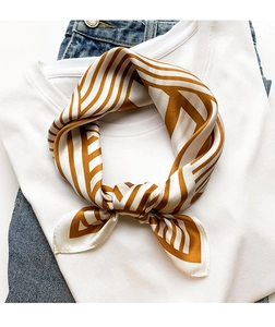 Detail of leaf pattern silk scarf knotted on white t-shirt and blue jeans outfit