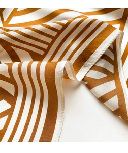 Close-up of caramel and cream striped silk scarf with fine stitched edges and smooth texture