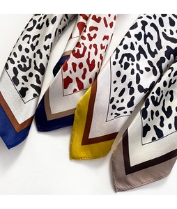 Detailed flat lay of leopard print silk scarves in four different elegant color schemes