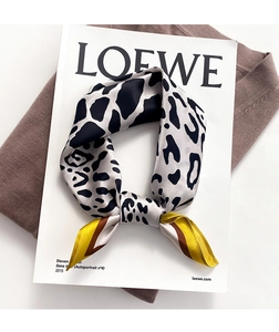 Detailed view of leopard print silk scarf styled over a brown knit sweater