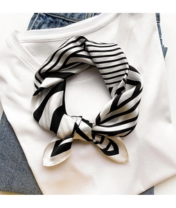 Detail shot of black and white striped silk neck scarf tied on a white cotton shirt