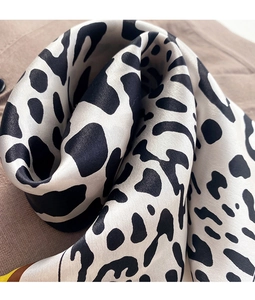 Macro shot of leopard print satin scarf featuring smooth silk texture and edge detail