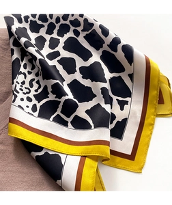 Detail of silk scarf with black and white giraffe print and yellow contrast borders