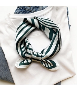 Close-up of green striped satin scarf tied on a white t-shirt for styling detail