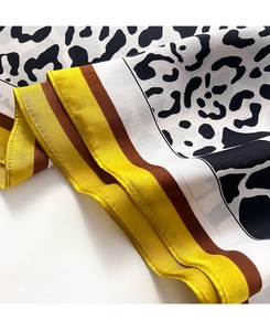 Detail of leopard print silk scarf showing twill texture and yellow contrast border