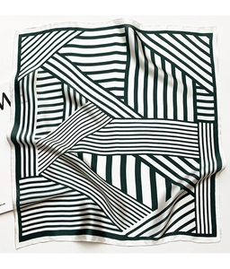 Detail of a square silk scarf featuring dark green and white geometric striped patterns