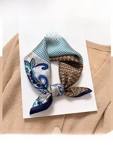 Detail of silk square scarf featuring blue paisley and geometric patterns on a sweater